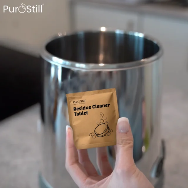 PuroStill residue cleaner tablet held in front of a water distiller