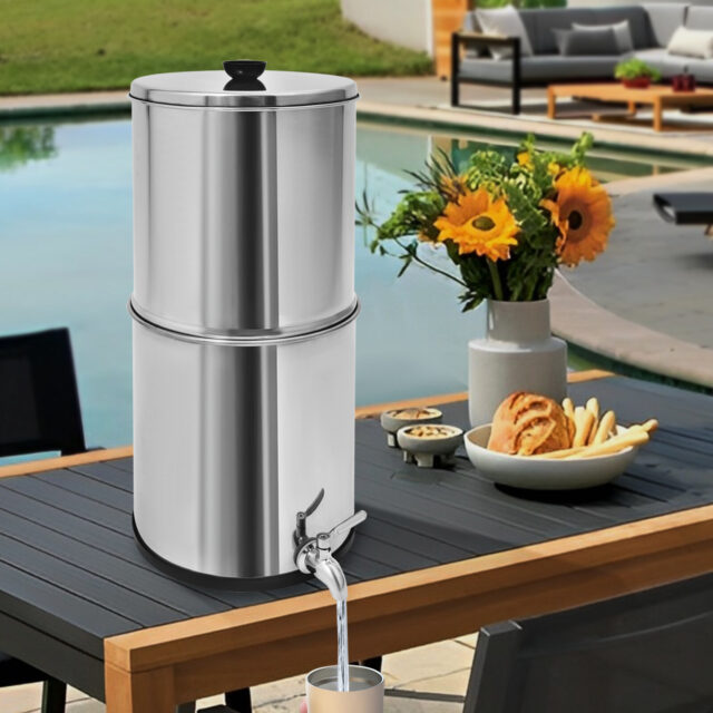 Stainless steel gravity-fed water filter system in a garden setting