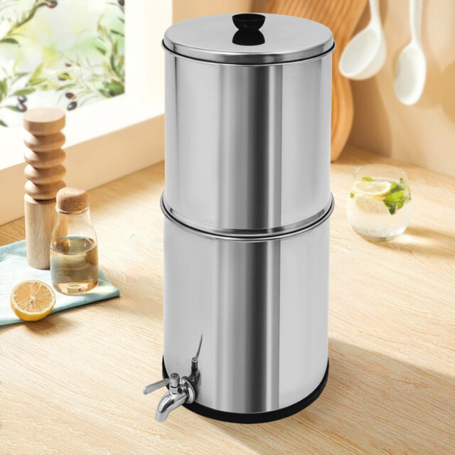 Stainless steel gravity-fed water filter system on a wooden surface