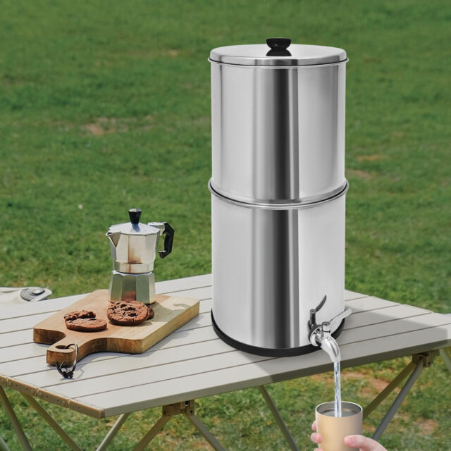 Gravity-fed water filter system with two filters on a table outdoors.